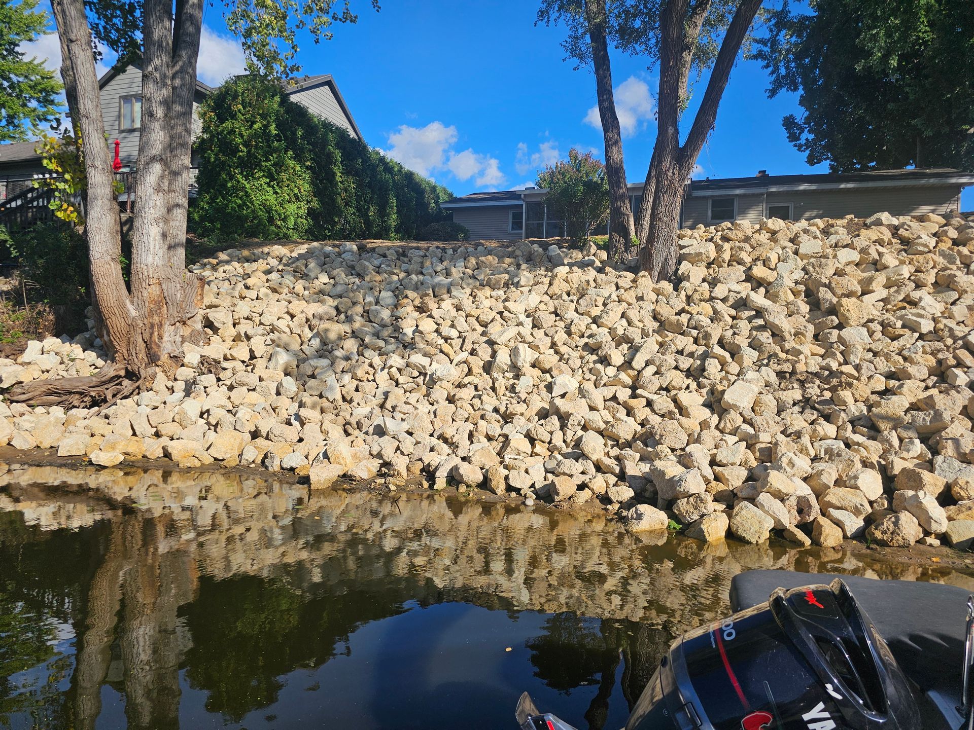 A large pile of rocks sits next to a body of water