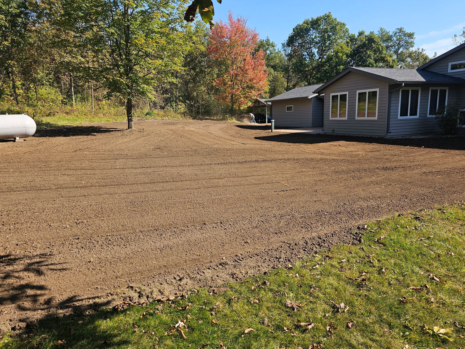 A house is sitting in the middle of a dirt field.