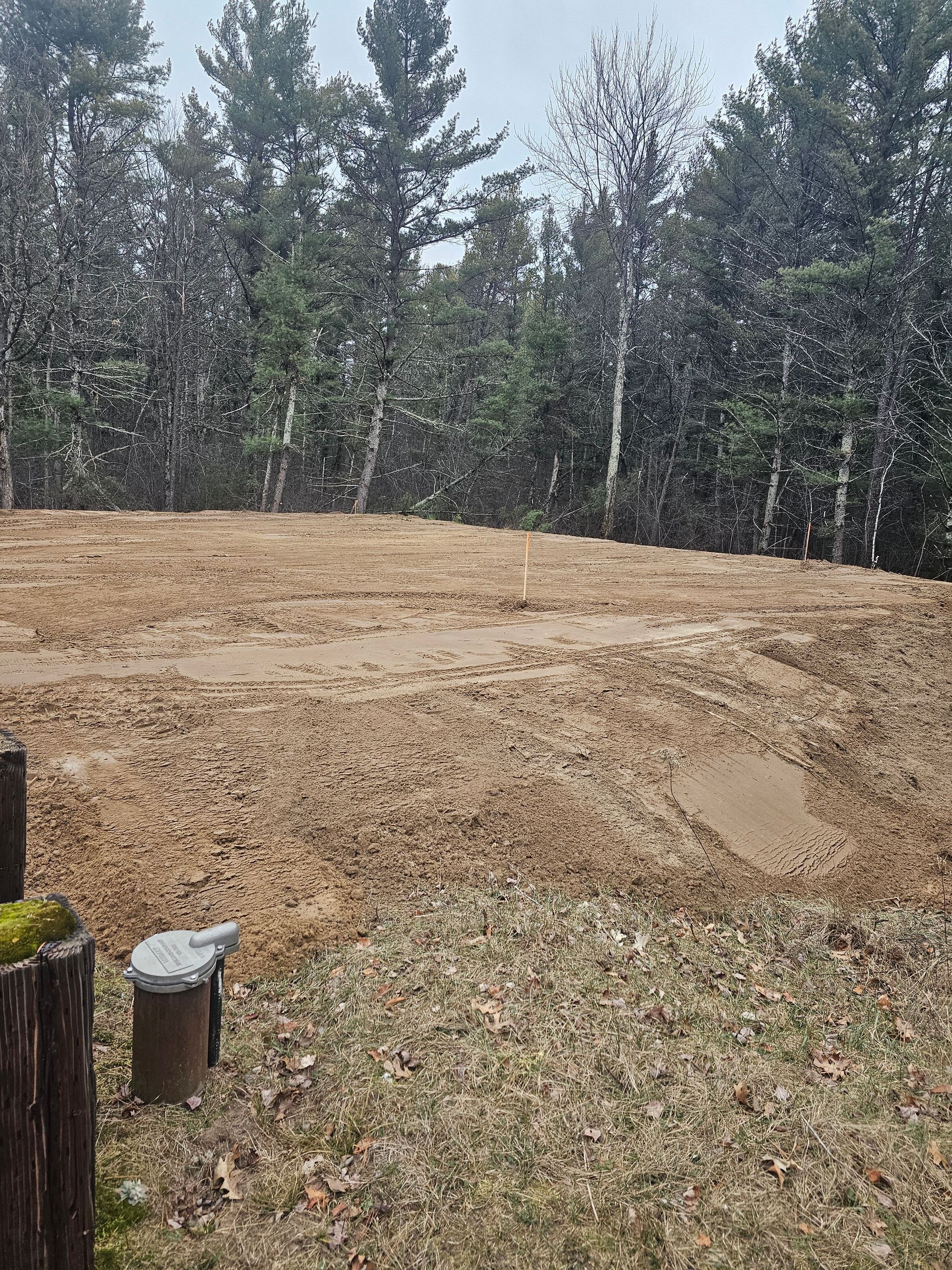 A large dirt field with trees in the background.