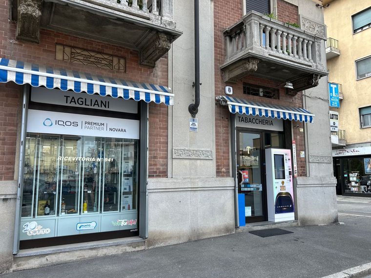 Due vetrine con tende da sole blu e bianche. Una reca la scritta