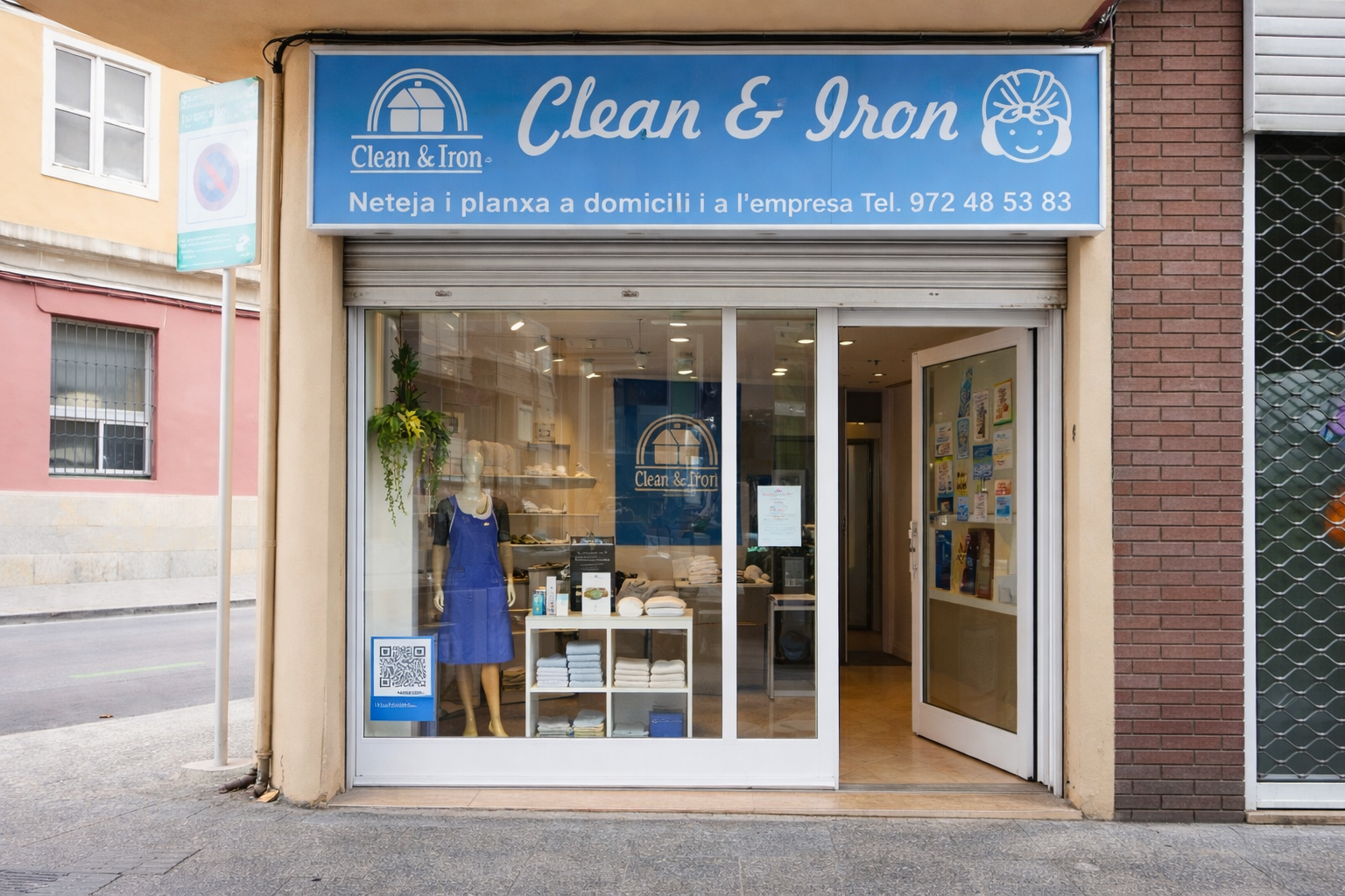 Empresa de limpieza con agencias físicas reales. The Clean & Iron storefront with a blue sign, glass front, open door, and a display mannequin in a dress.