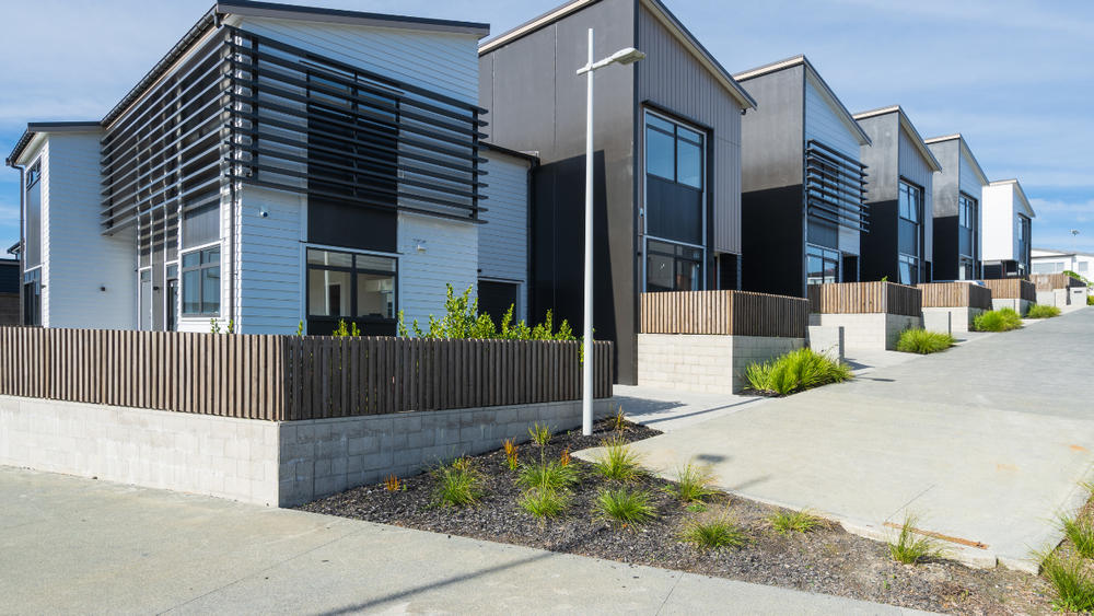 Row of modern townhouses with dark accents, brick facades, and slatted window coverings.