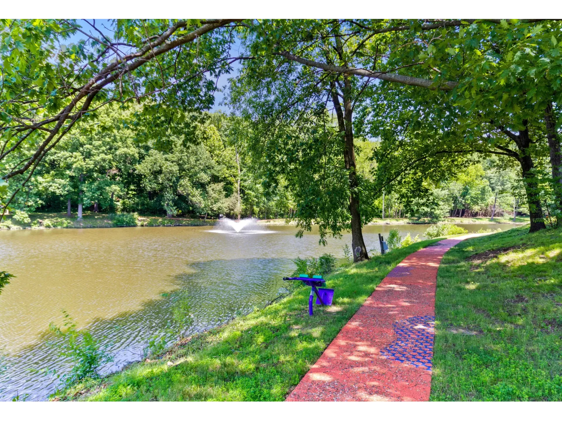 Serene lakeside view with a walking pathway and fountain in the background.