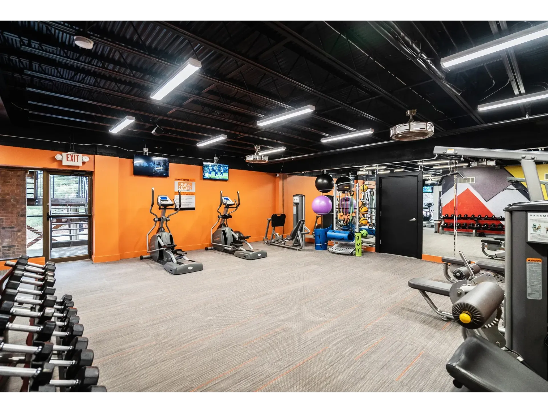 Interior view of a modern gym with exercise equipment and bright walls.