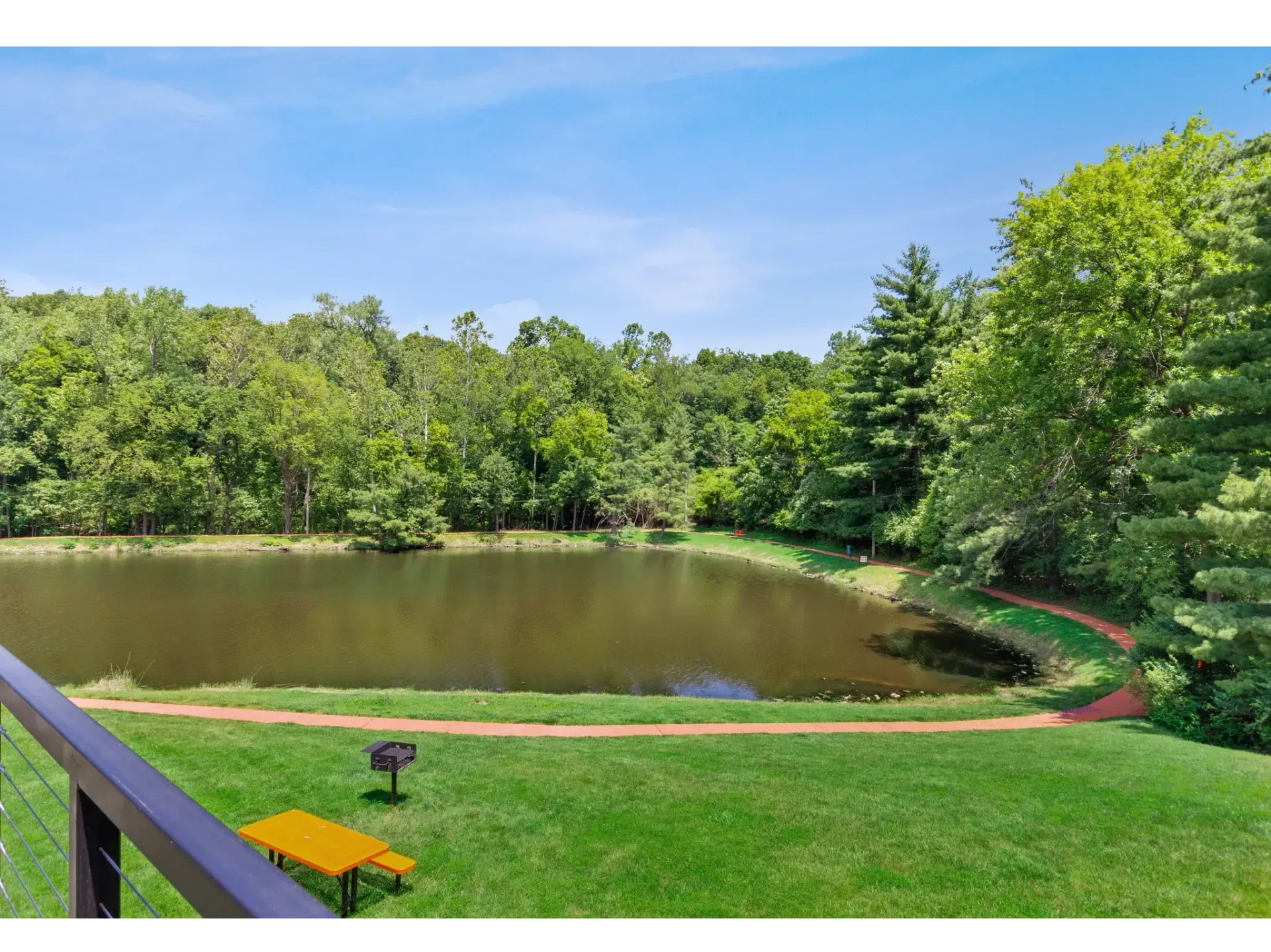 Scenic view of a pond surrounded by greenery and a walking path.