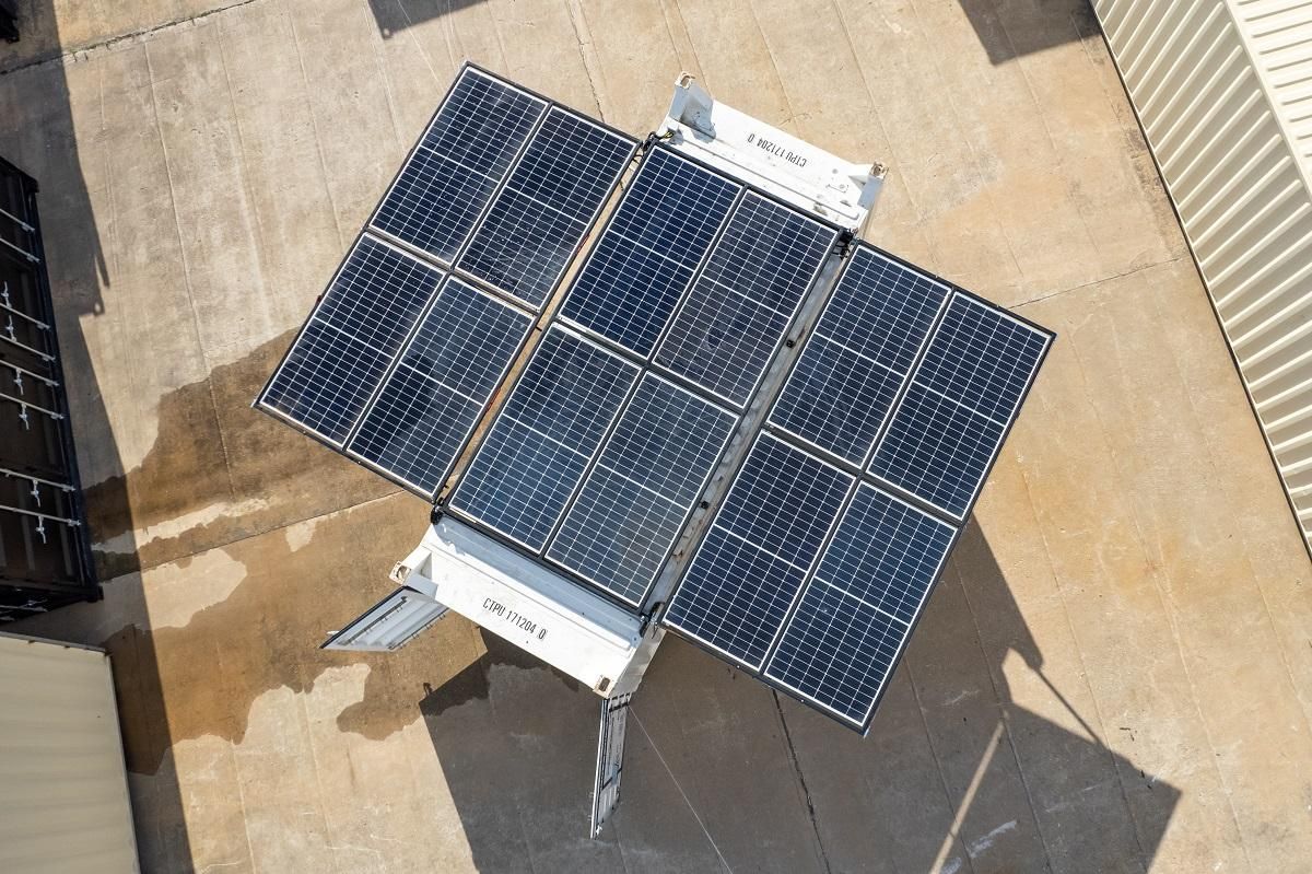 Overhead view of a solar panel array mounted on a white trailer on a concrete surface.