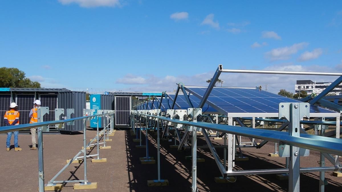 Solar panels on a rooftop, with a worker, blue sky, and support structures.