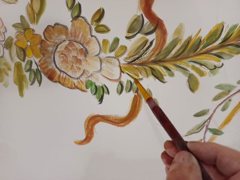 Dipingere a mano un disegno floreale e di foglie su carta bianca con un pennello sottile.