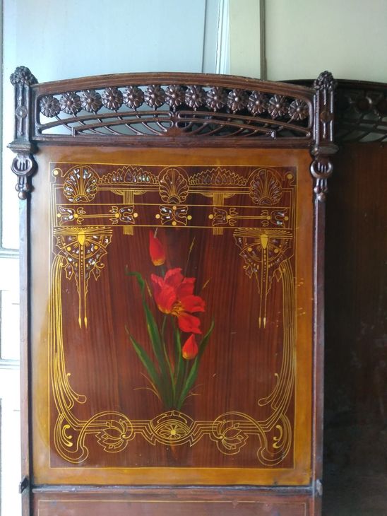 Ornato mobiletto in legno scuro con intarsi dorati e un motivo floreale rosso sul pannello frontale