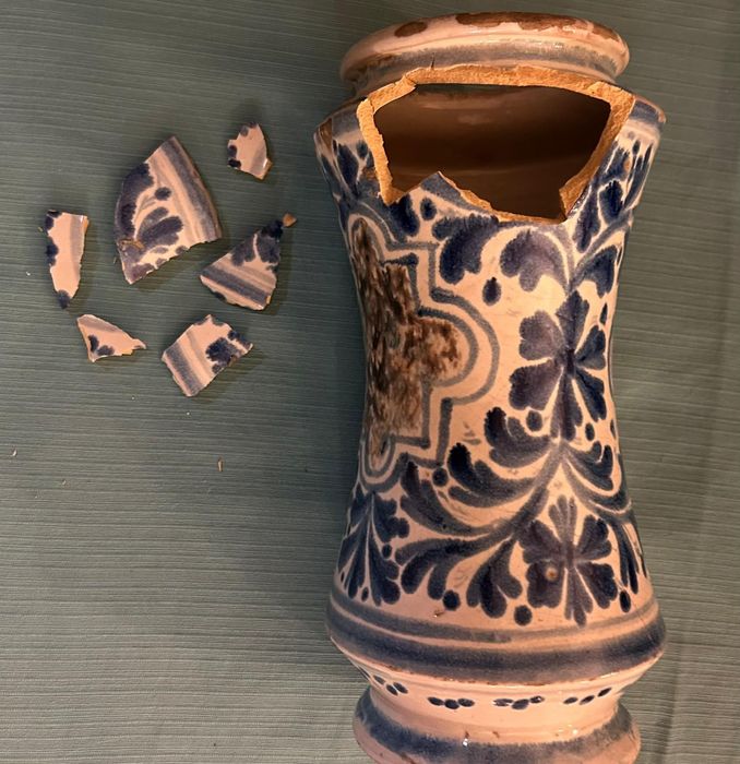 Vaso di ceramica blu e bianco rotto, con i frammenti sparsi accanto su una superficie ruvida