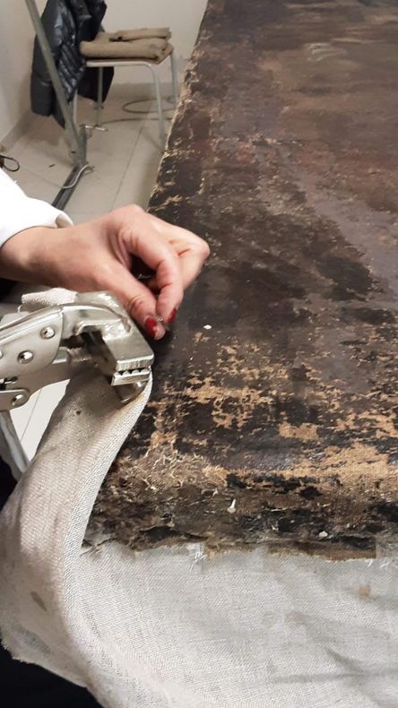 Fissaggio manuale di un tessuto scuro a una superficie imbottita bianca su un banco da lavoro