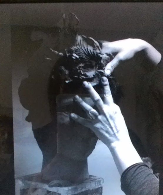 Persona che si sistema i capelli in un selfie in bianco e nero, parzialmente coperta dalle mani in una stanza buia