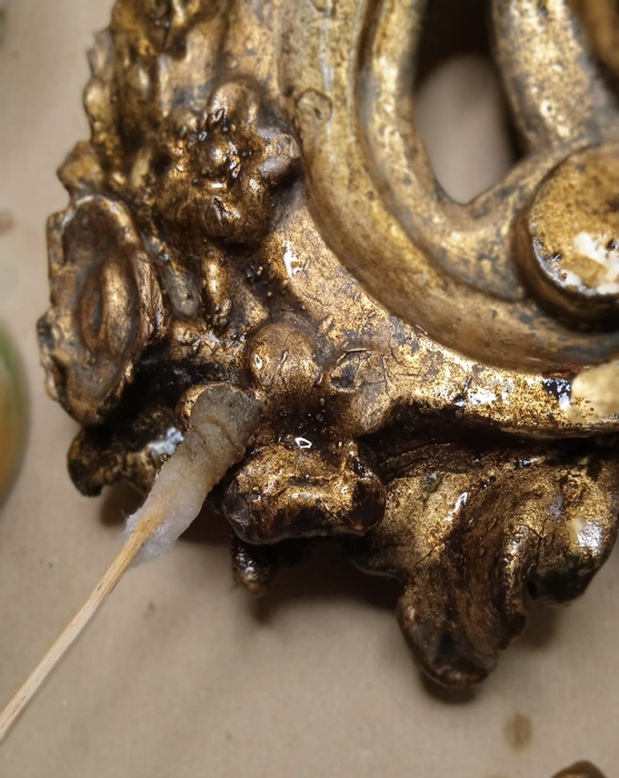 Primo piano di un dettaglio ornamentale in metallo dorato con un piccolo cavo o filo attaccato