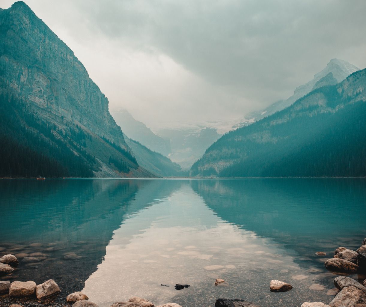A lake surrounded by mountains on a cloudy day