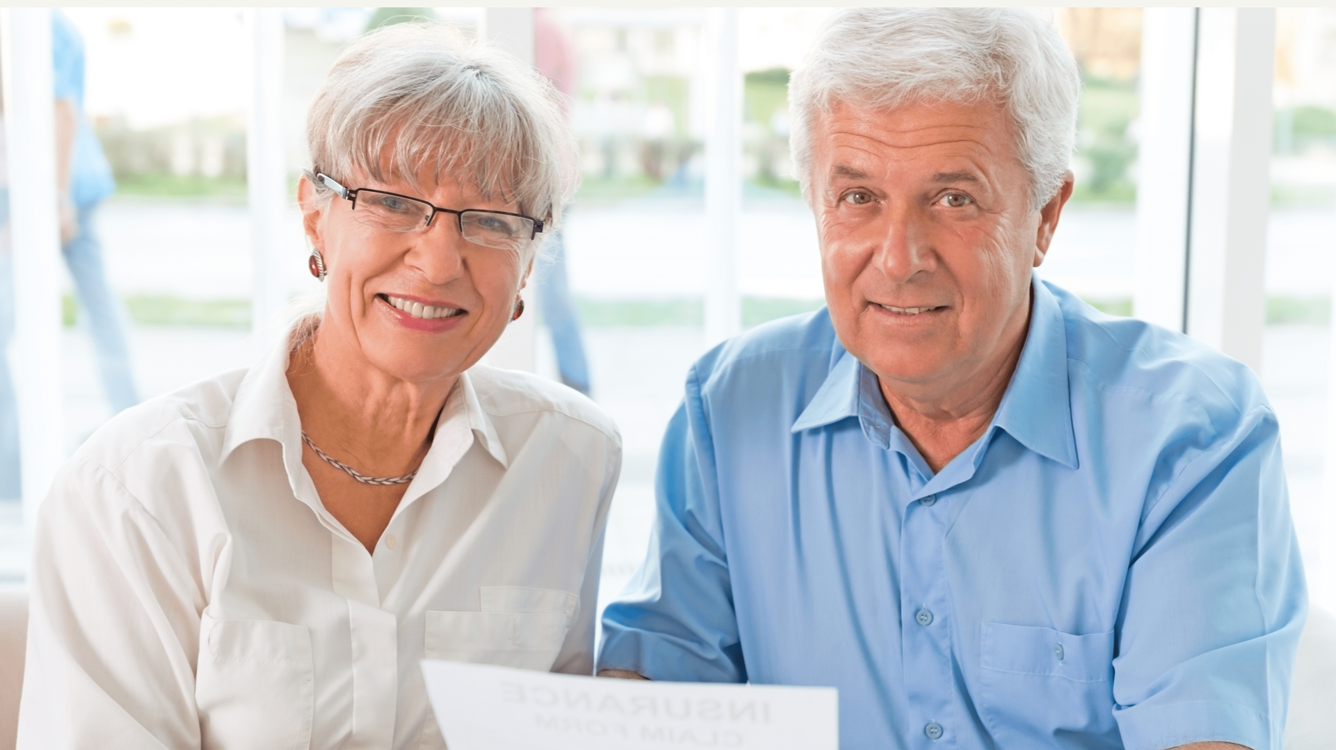 A man and a woman are sitting next to each other holding a piece of paper.