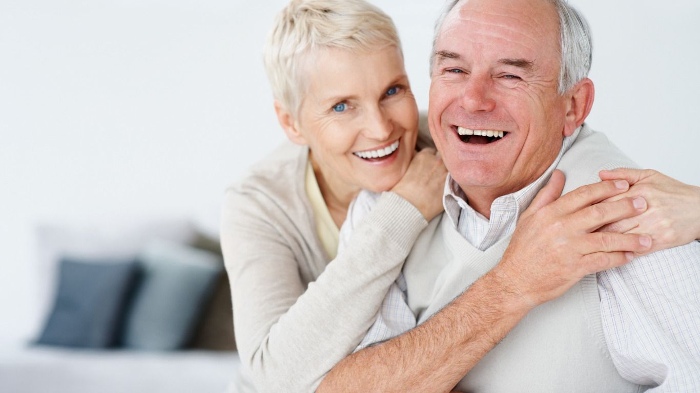 A man and a woman are hugging each other and smiling.
