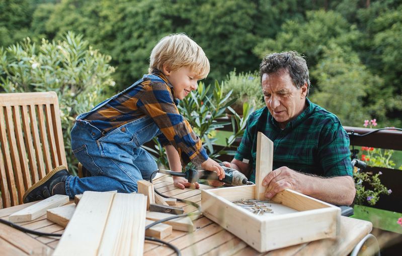A man and a boy are working on a wooden table.