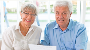 A man and a woman are sitting next to each other looking at a piece of paper.