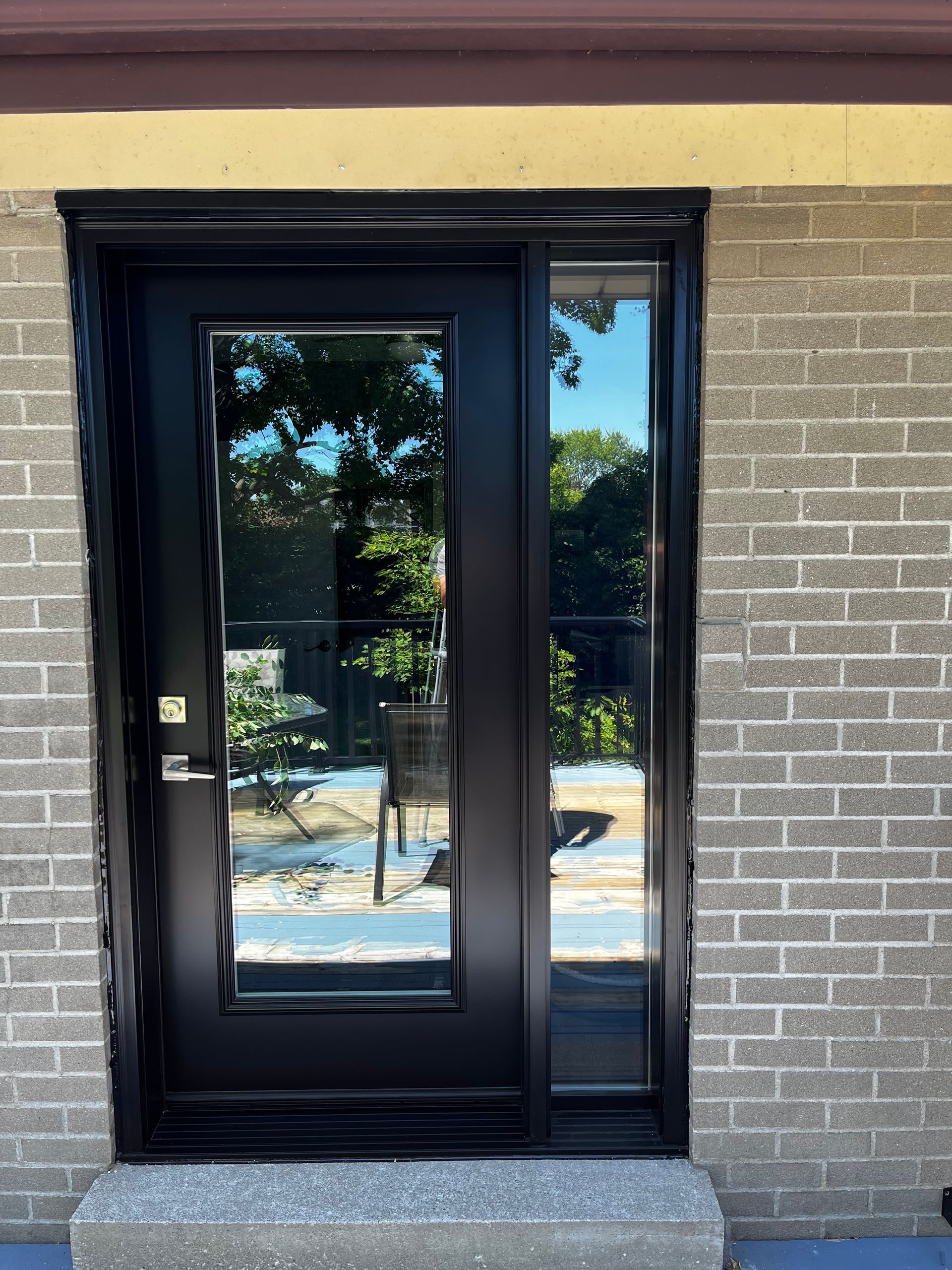 A black door with a glass window is on a brick building.