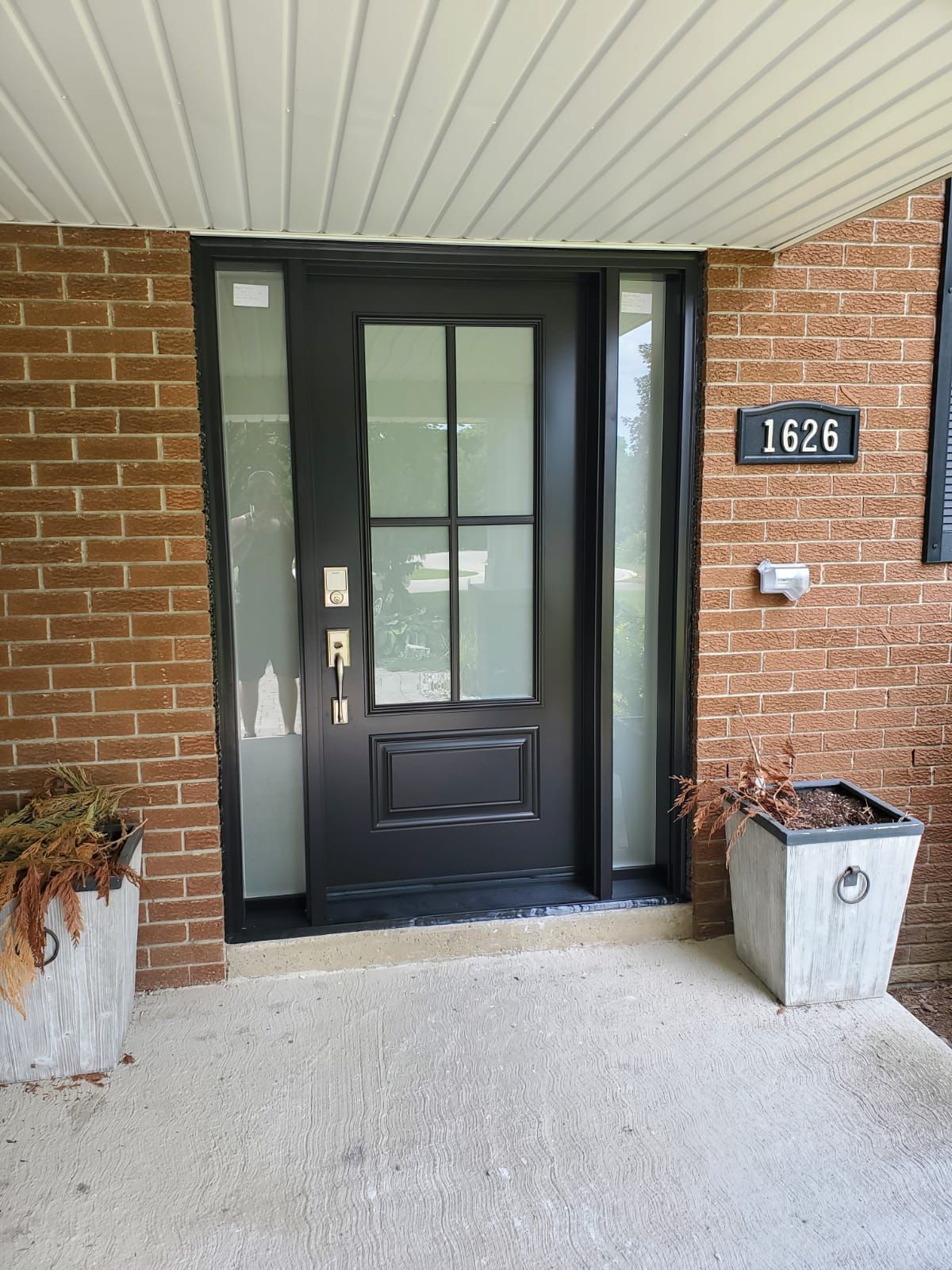 Front entrance with black door, brick walls, and house number 1626 above planters