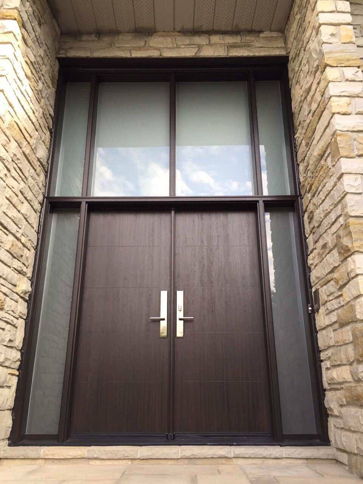 A large wooden door with a lot of windows on a brick building.