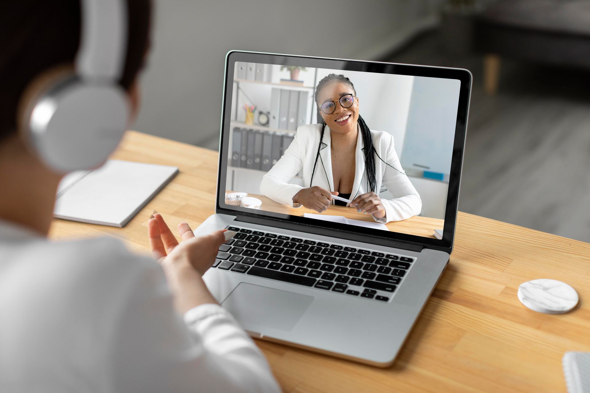 Chamada de vídeo em um laptop com um médico sorridente em um consultório bem iluminado.