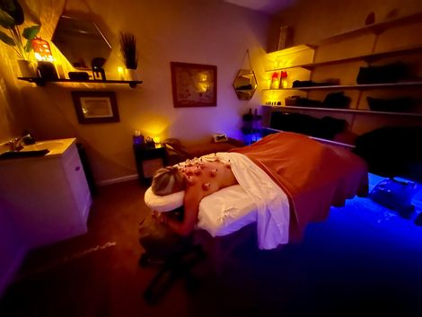 Massage therapist working on a man lying on a table in a dimly lit spa room
