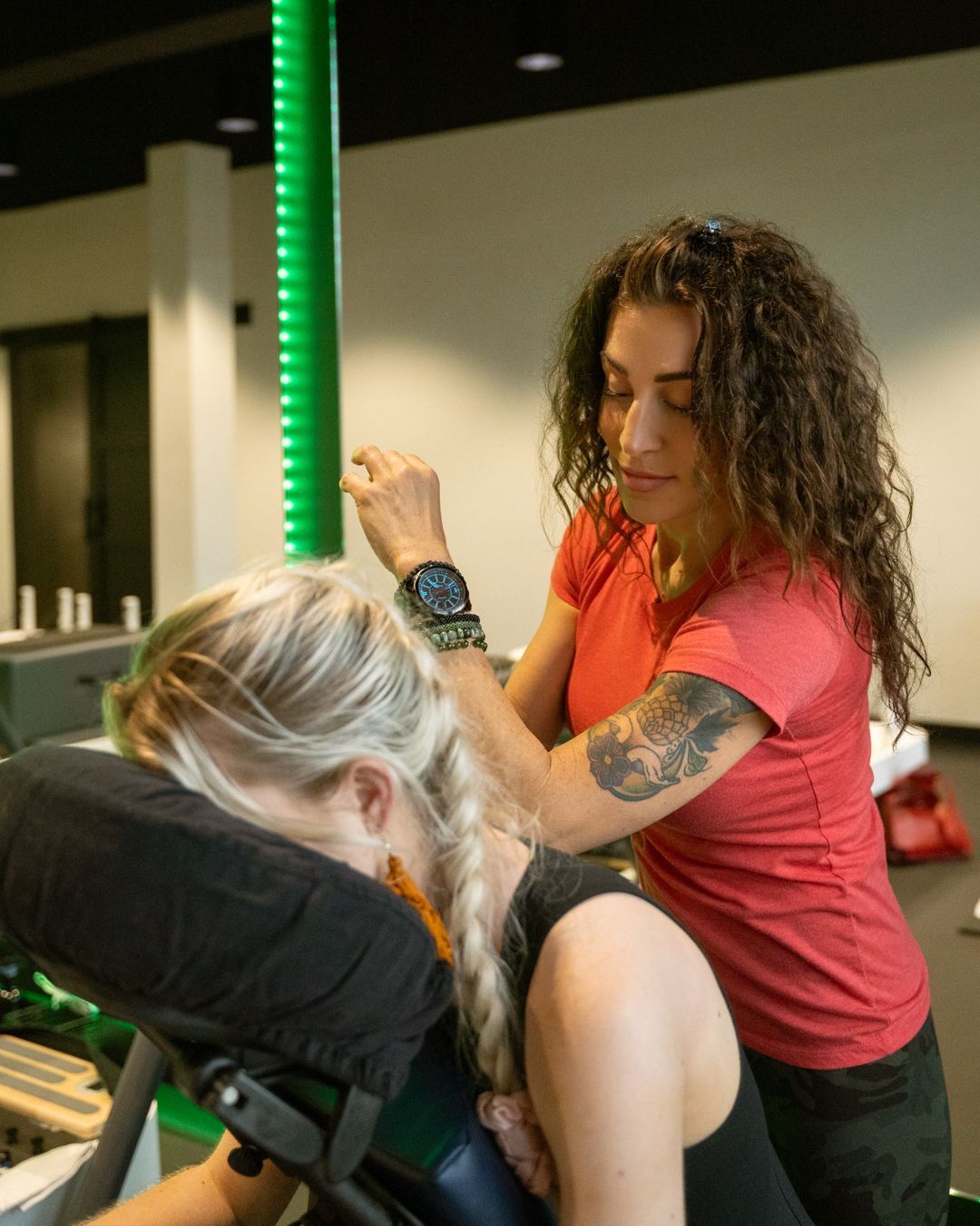 A practitioner performs physical therapy, stretching the arm of a person lying on a massage table.