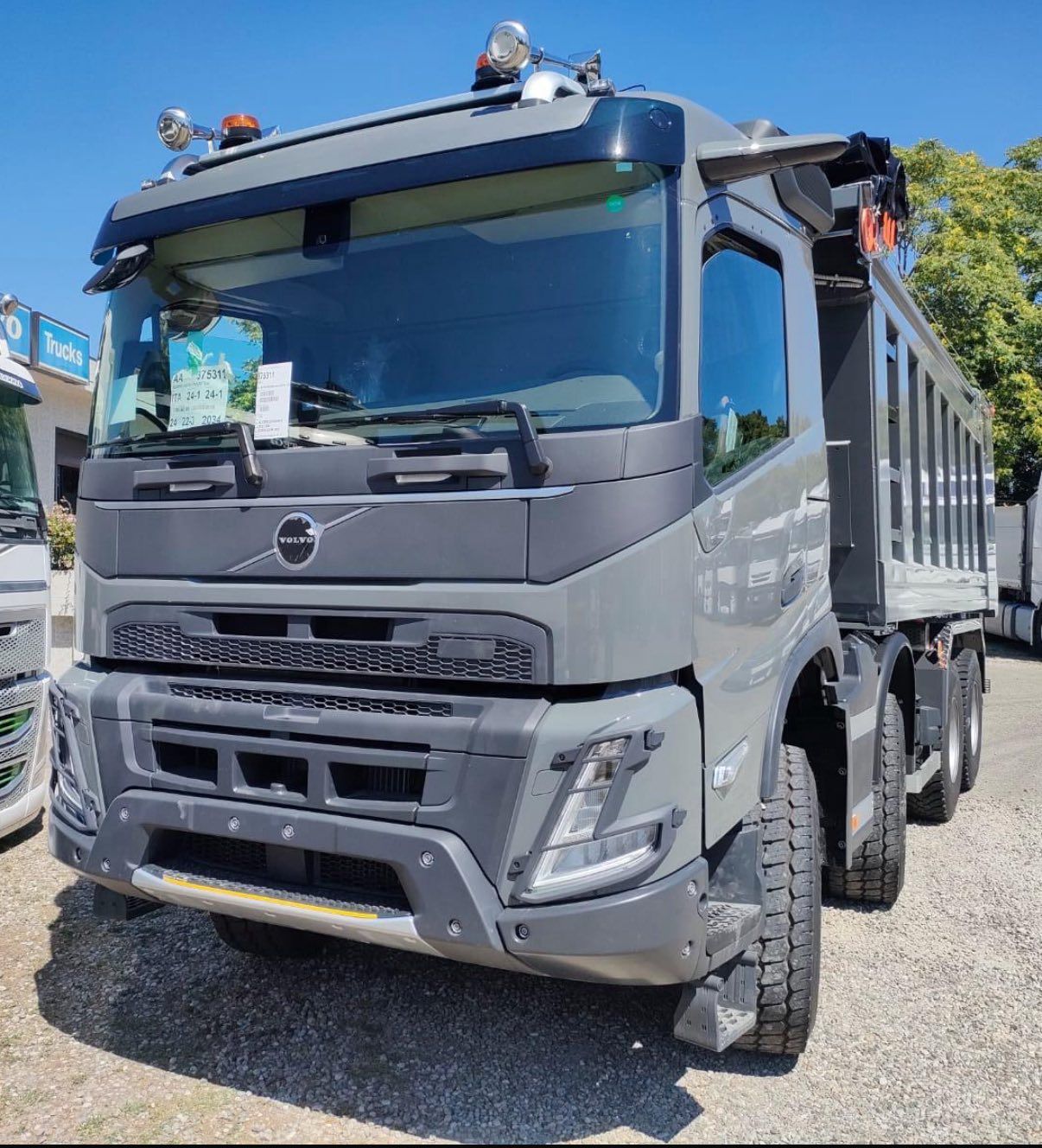 Autocarro con cassone ribaltabile Volvo grigio parcheggiato sulla ghiaia.
