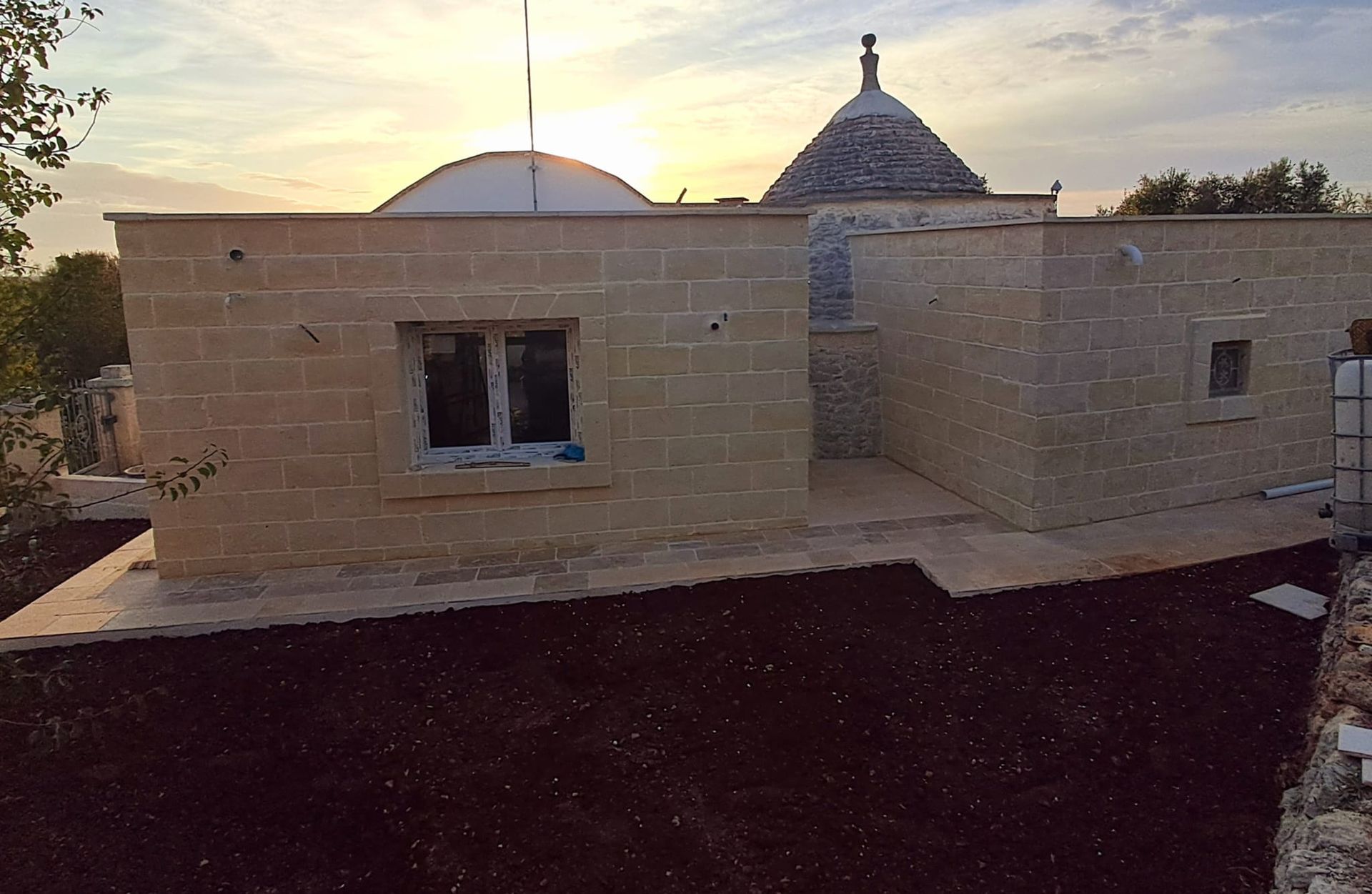 Edificio in pietra con una piccola finestra e un tetto a cupola al tramonto