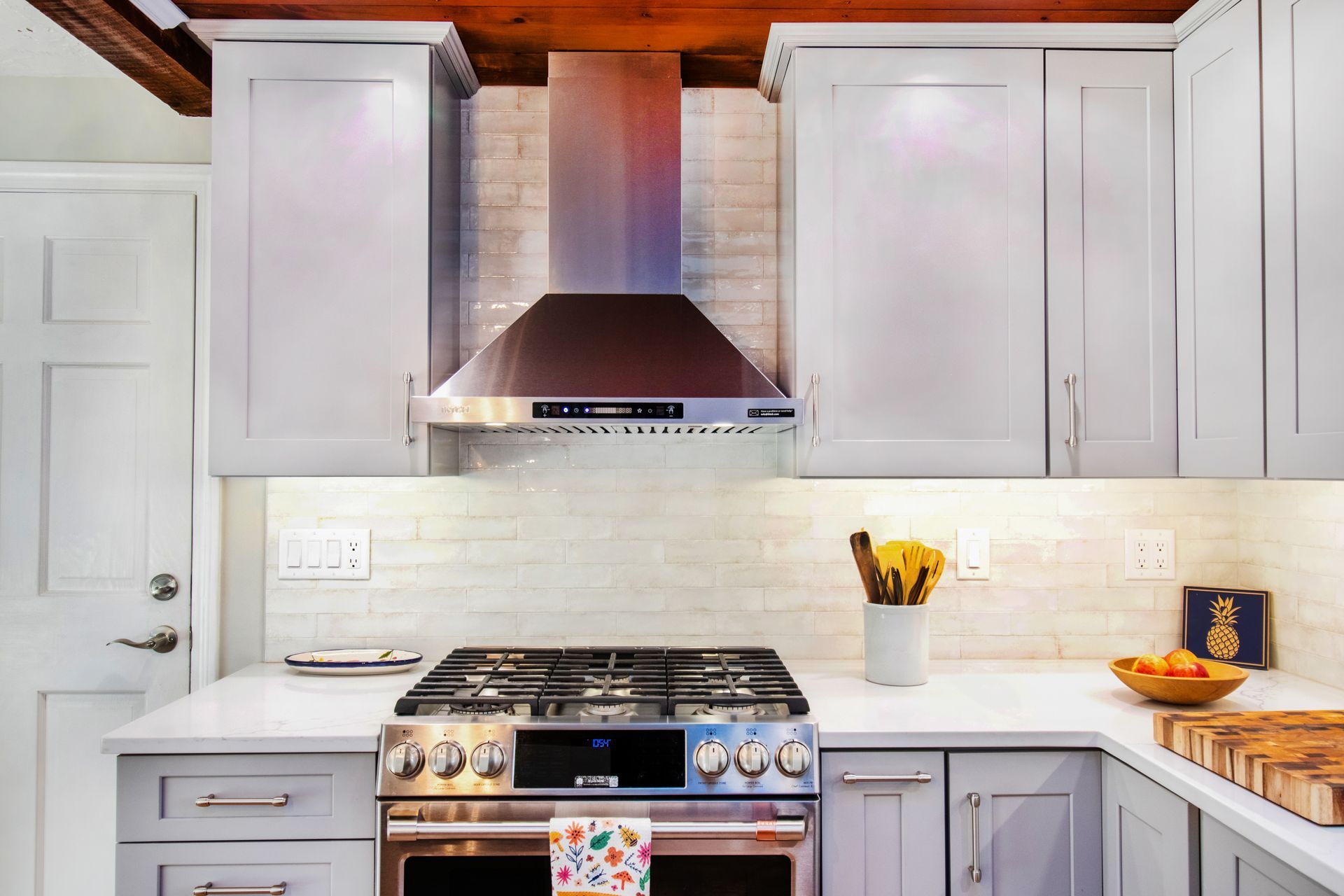 Modern kitchen with stainless steel appliances, light gray cabinets, and white countertops.