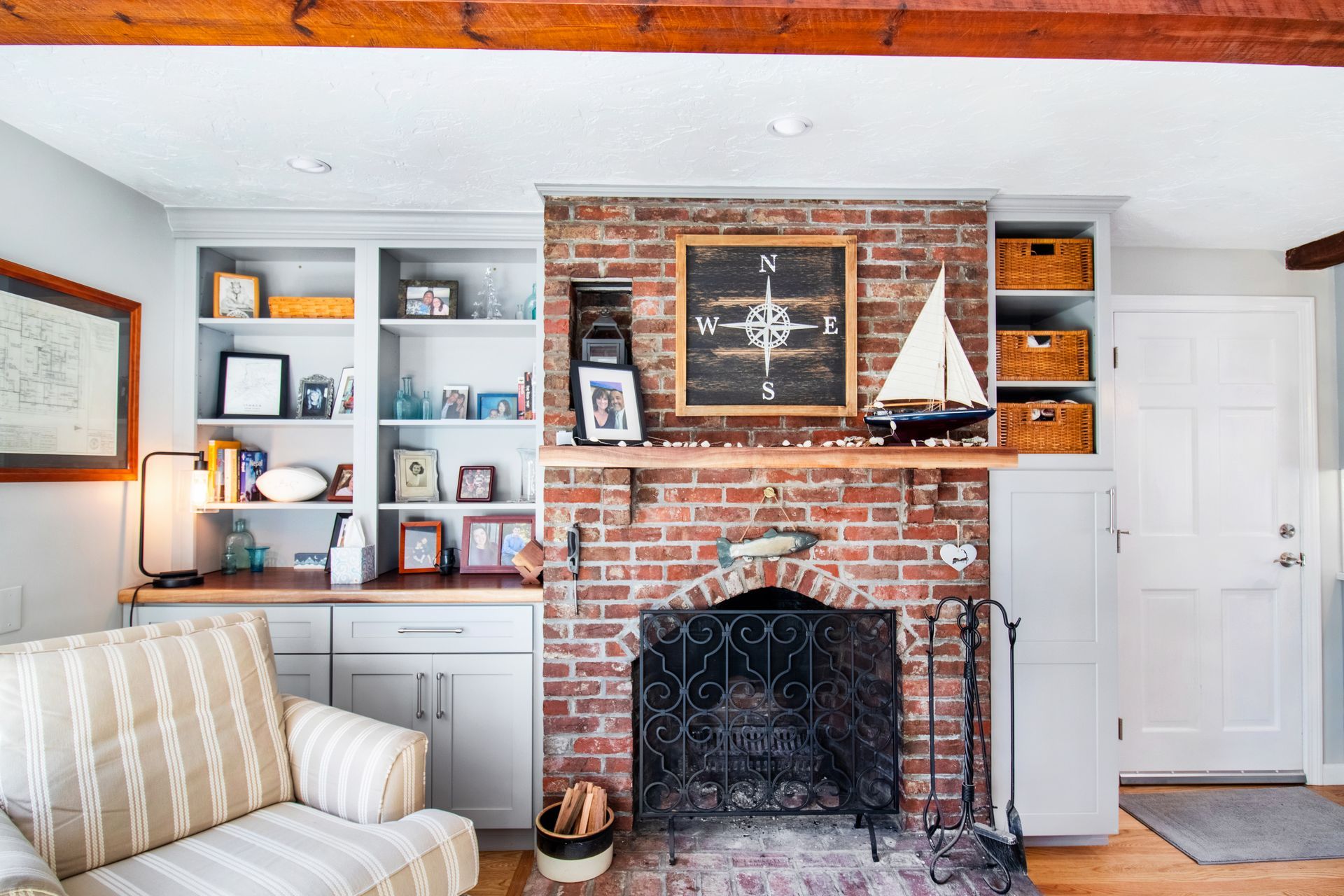 Fireplace with brick surround, built-in shelves, framed nautical artwork, and a model sailboat in a cozy living room.