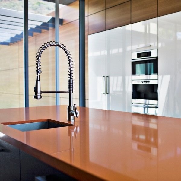 Kitchen with orange countertop, stainless steel faucet, and white cabinets.