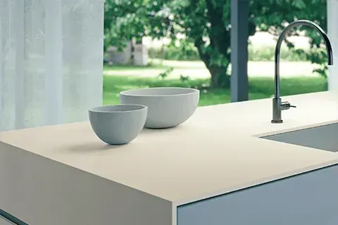 Modern kitchen countertop with two bowls, a faucet, and a view of trees.