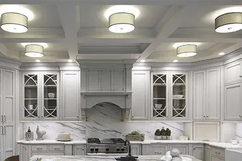 White kitchen with marble backsplash, cabinets, and drum-shaped ceiling lights.