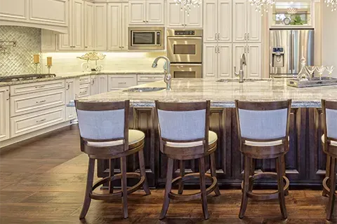 Kitchen with white cabinets, dark island, and bar stools.
