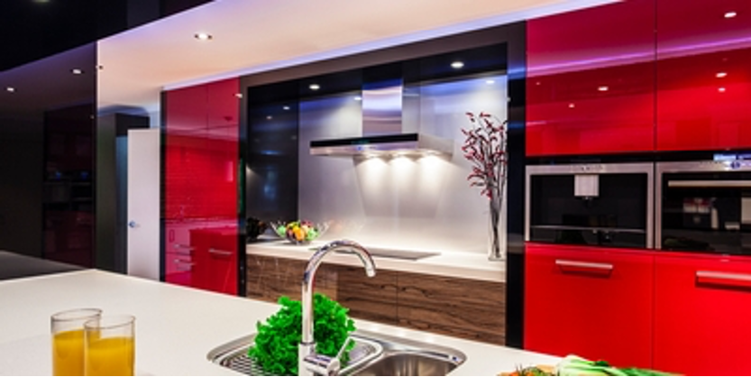 Modern kitchen with red cabinetry, stainless steel appliances, and a white countertop.