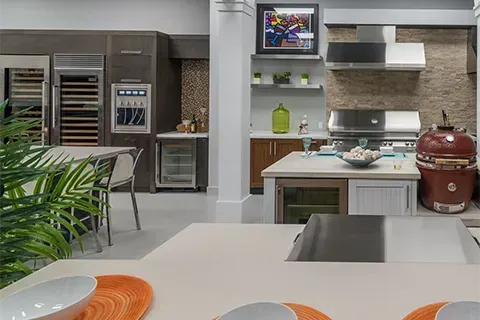 Modern outdoor kitchen with grill, smoker, and appliances in showroom.