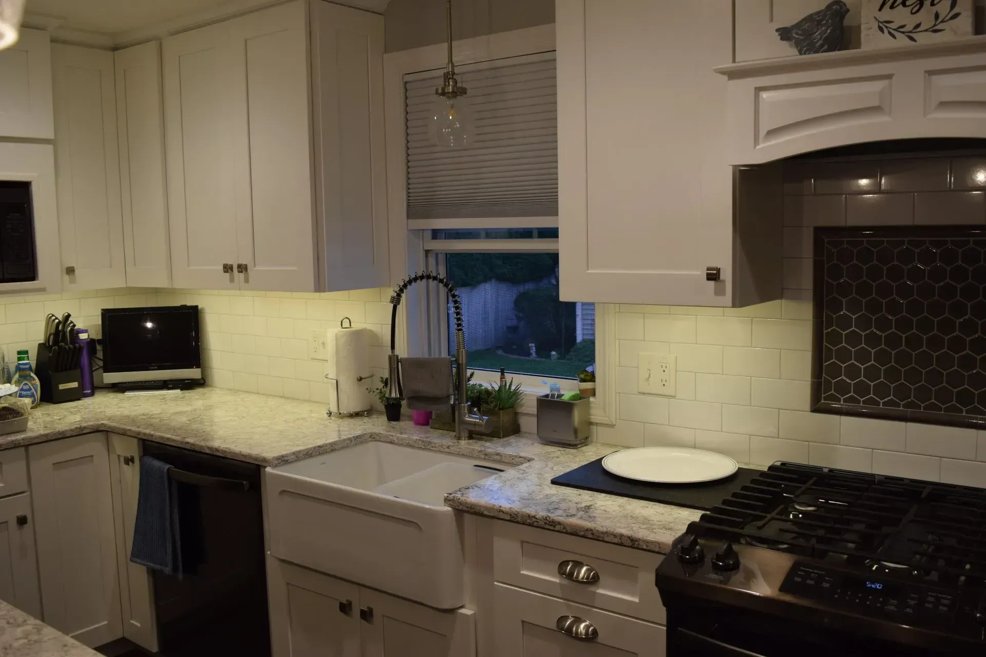 Kitchen with white cabinets, farmhouse sink, granite countertops, and a gas stove.