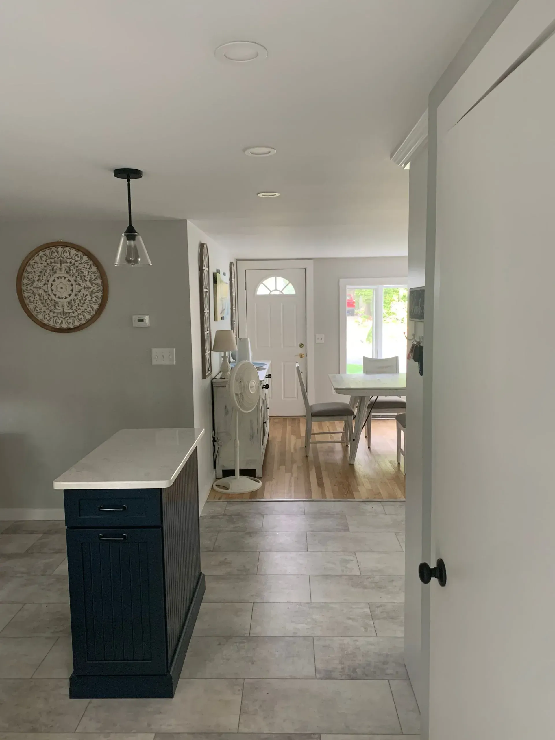 Kitchen island with dark blue cabinetry, view into dining room, front door visible.
