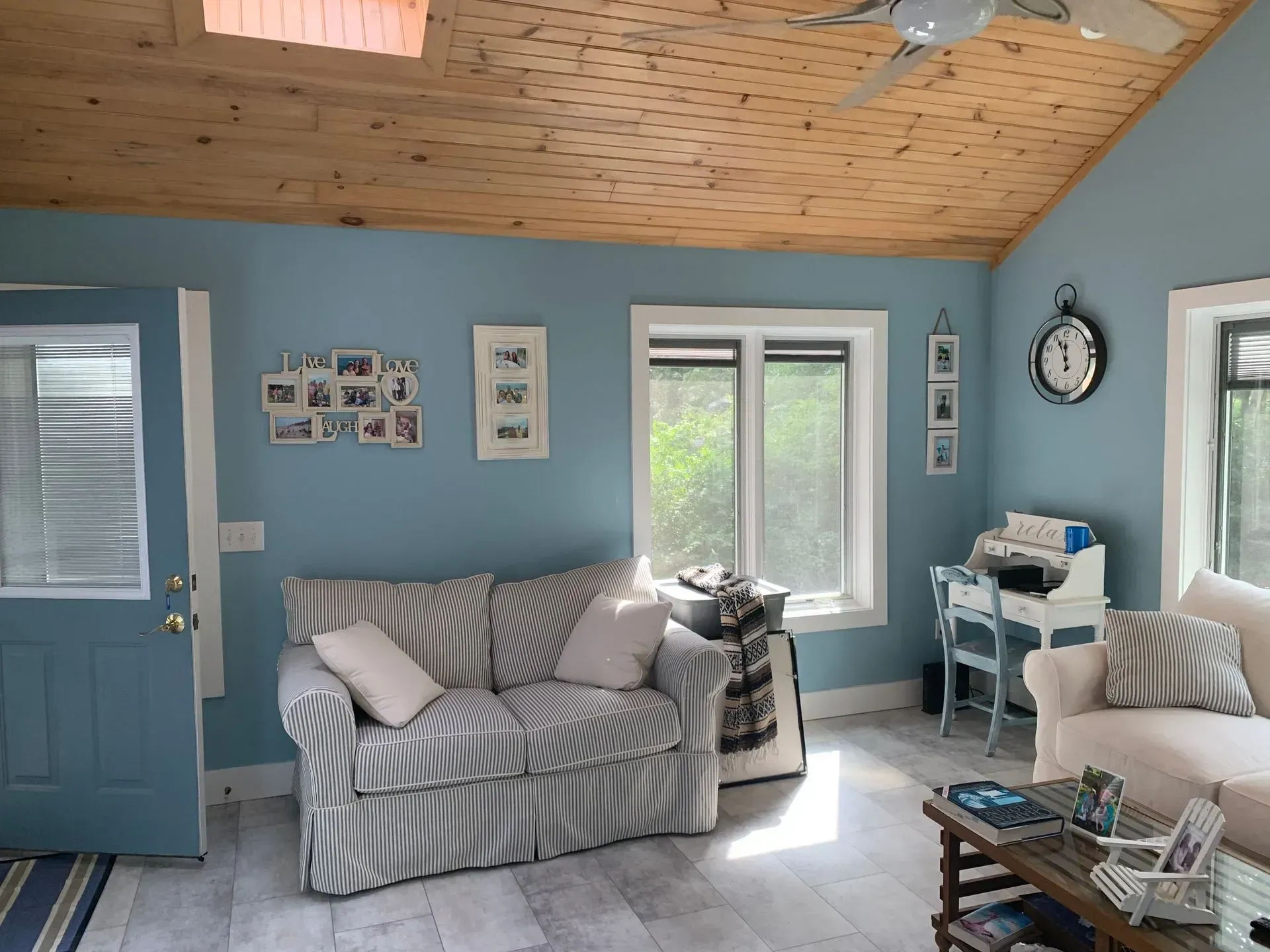 Cozy living room with blue walls, striped sofa, light wood ceiling, and white trim.