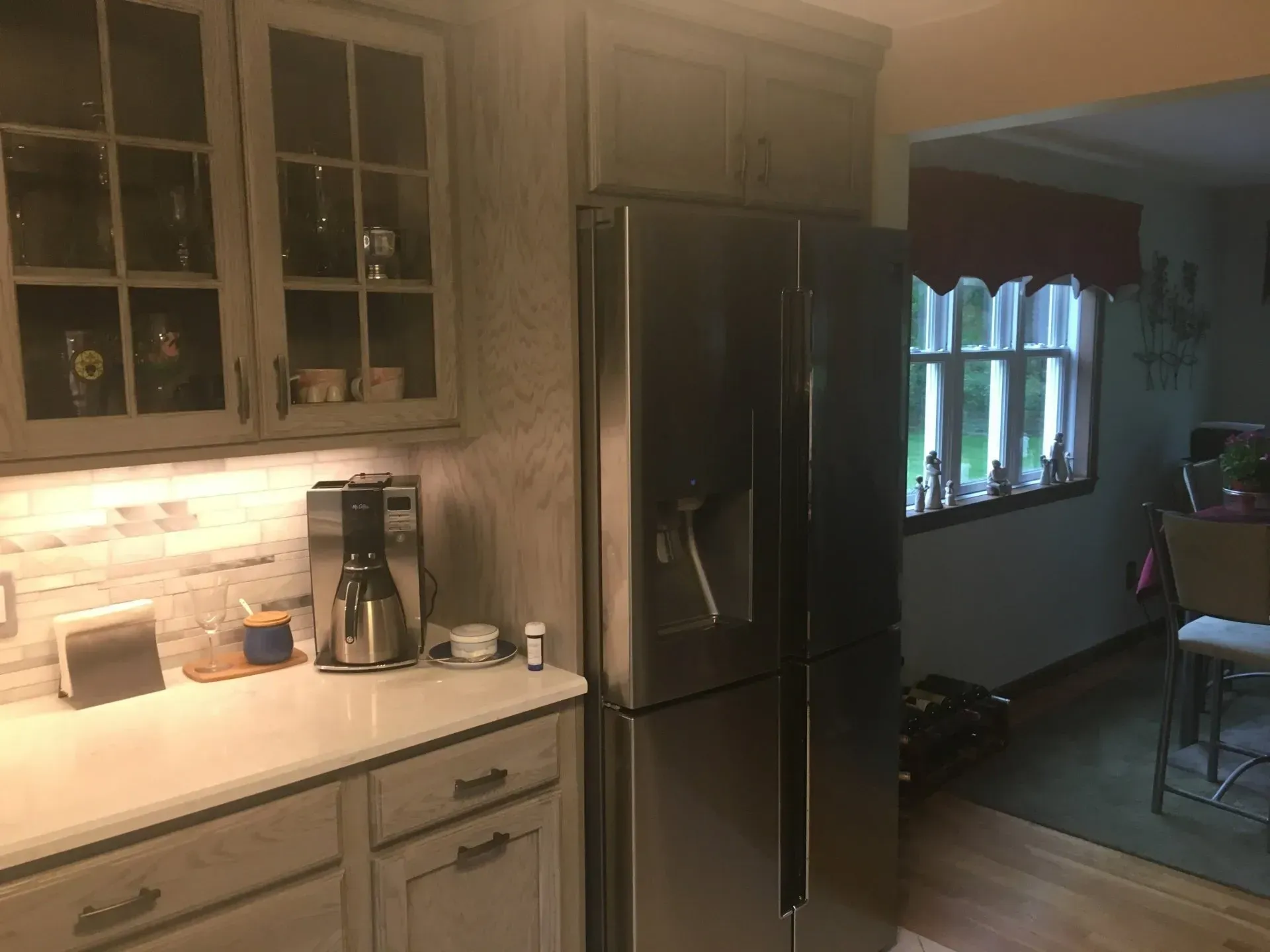 Kitchen with gray cabinets, stainless steel refrigerator, and a window.