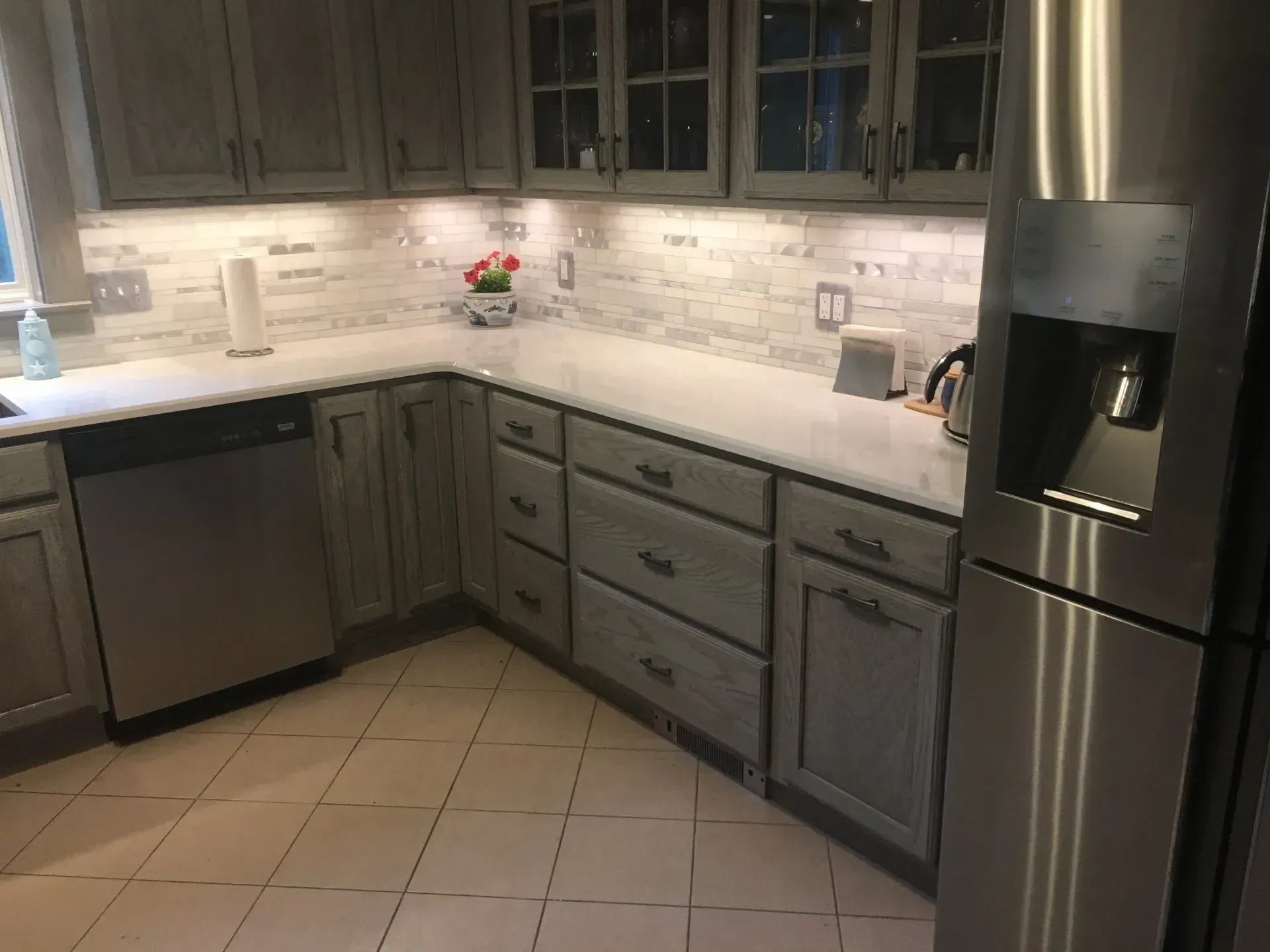 Kitchen with gray cabinets, marble countertops, stainless steel appliances, and tile floor.