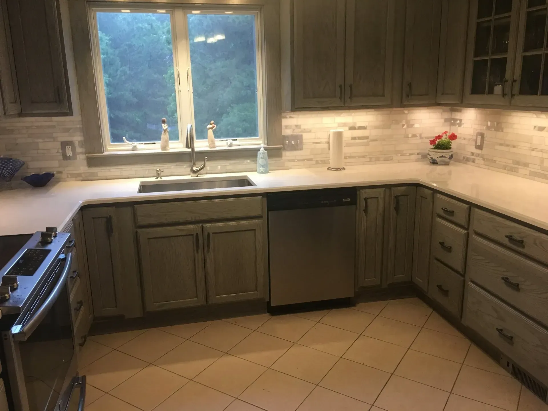 Gray kitchen with white countertops, backsplash, and stainless steel appliances.