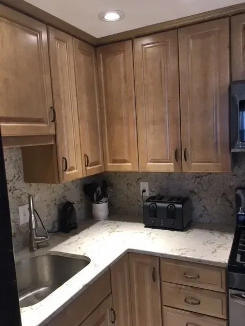 Kitchen with light wood cabinets, granite countertops, and a stainless steel sink.