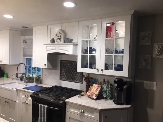 White kitchen with cabinets, stove, sink, and decorative items.