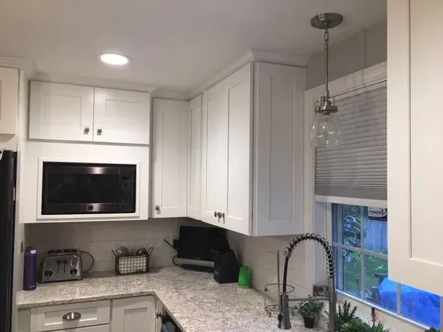 Bright kitchen with island, pendant lights, wood floors, and patterned wallpaper.