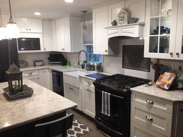 White kitchen with black stove, white cabinets, and granite countertops.