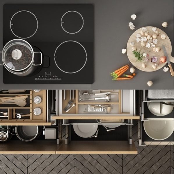 Top-down view of kitchen setup with an induction cooktop, cutting board with vegetables, and organized cabinetry with utensils and bowls.