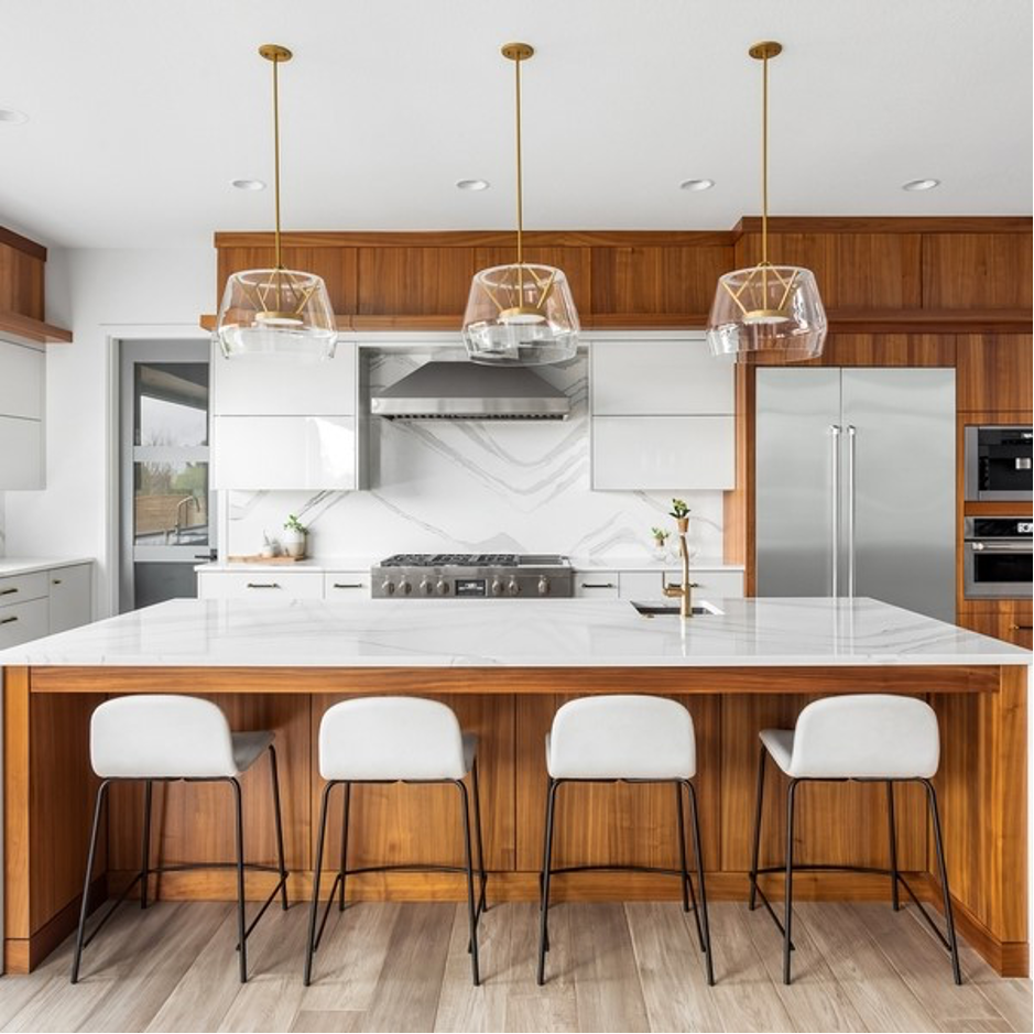 Modern kitchen with wood cabinets, white island, and gold pendant lights.